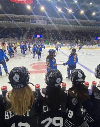 Young hockey players watching from the rinkside bench